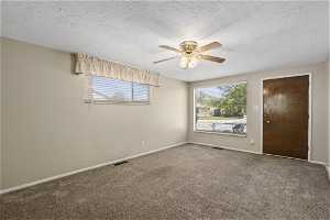 Carpeted family room featuring ceiling fan and a textured ceiling