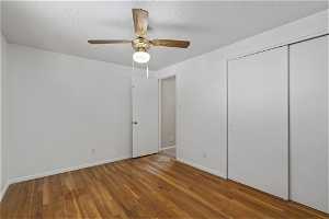 Unfurnished bedroom with a closet, light hardwood / wood-style flooring, ceiling fan, and a textured ceiling