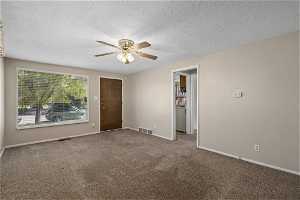Family room with carpet, ceiling fan, and big window to let in natural light.