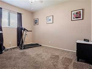 Bedroom or Exercise room featuring dark colored carpet and ceiling fan