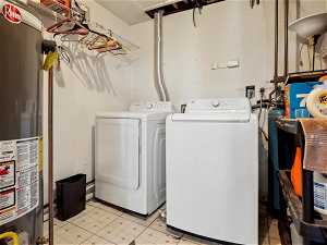 Washroom featuring water heater, washing machine and dryer, and light tile floors