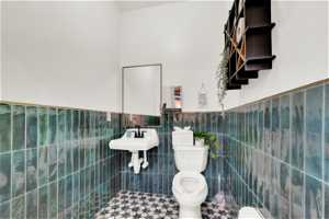 Bathroom with tile walls, toilet, tile flooring, tasteful backsplash, and sink