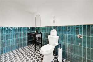 Bathroom with toilet, tile flooring, and tile walls