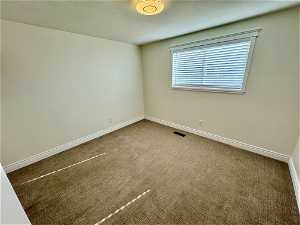 Empty room with a textured ceiling and carpet floors