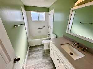 Full bathroom featuring hardwood / wood-style floors, vanity, tiled shower / bath combo, and toilet