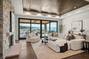 Living area with a raised ceiling, dark wood-style flooring, wooden ceiling, a stone fireplace, and a mountain view