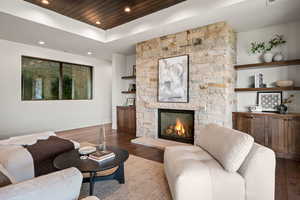 Living room featuring a fireplace, wood finished floors, recessed lighting, a raised ceiling, and wooden ceiling