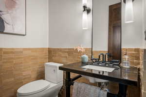 Half bath with wainscoting and tile walls