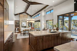 Kitchen with beamed ceiling, hanging light fixtures, dark wood-style flooring, high vaulted ceiling, and a chandelier