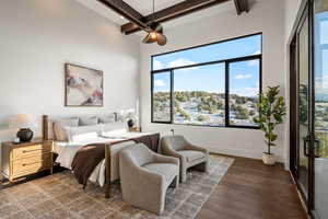 Bedroom with dark wood-type flooring, beamed ceiling, access to exterior, and ceiling fan