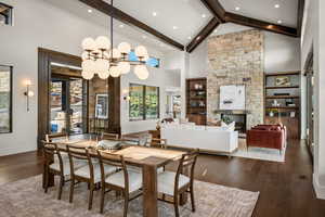 Dining area with a fireplace, high vaulted ceiling, dark wood-style flooring, healthy amount of natural light, and built in shelves