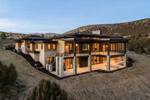 Rear view of property featuring stone siding, a patio area, stairs, a chimney, and a mountain view