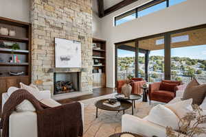 Living room with a stone fireplace, a towering ceiling, built in features, and wood finished floors