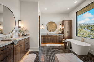 Full bath featuring two vanities, a freestanding tub, and recessed lighting