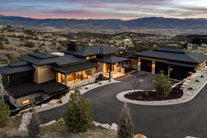 Back of house featuring asphalt driveway, an attached garage, stone siding, a mountain view, and a chimney