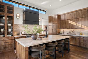Kitchen featuring tasteful backsplash, dark wood-style flooring, a kitchen bar, and recessed lighting