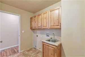 Laundry room with cabinets, sink, hookup for a washing machine, hookup for electric dryer.