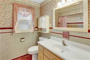 Bathroom with tile walls, oversized vanity, and toilet