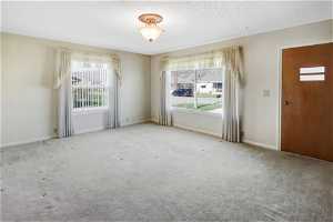 Carpeted empty room with a healthy amount of sunlight and a textured ceiling