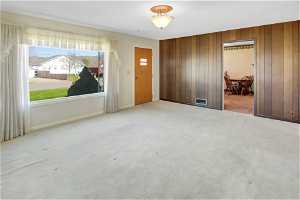 Empty room with light carpet and wood walls
