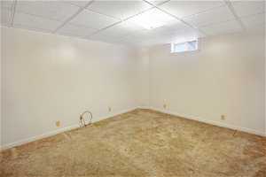 Basement featuring light carpet and a paneled ceiling