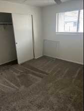 Unfurnished bedroom with dark colored carpet, a closet, and ceiling fan