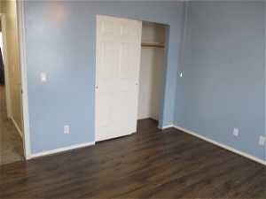 Unfurnished bedroom featuring dark hardwood / wood-style flooring and a closet