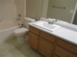 Full bathroom featuring tile floors, vanity, tub / shower combination, and toilet
