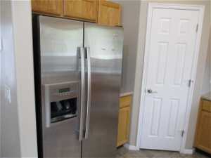 Kitchen with light tile flooring and stainless steel refrigerator with ice dispenser