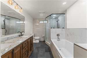 Full bathroom featuring tile walls, independent shower and bath, toilet, tile flooring, and dual vanity