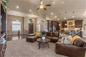 Living room featuring high vaulted ceiling, ceiling fan with notable chandelier, and hardwood / wood-style flooring