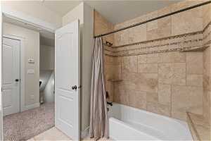Bathroom featuring tile flooring, shower / bath combo, and a textured ceiling