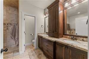 Bathroom with oversized vanity, tile floors, toilet, and dual sinks