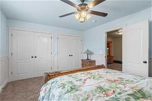 Carpeted bedroom featuring ceiling fan and two closets