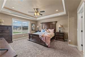 Carpeted bedroom featuring ornamental molding, a textured ceiling, ceiling fan, and a raised ceiling