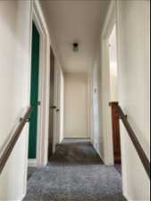 Hallway featuring dark colored carpet