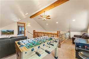Recreation room featuring lofted ceiling with beams, light carpet, and ceiling fan