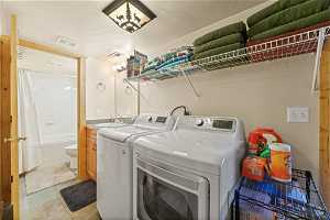 Washroom featuring light tile flooring, washer and dryer, and sink