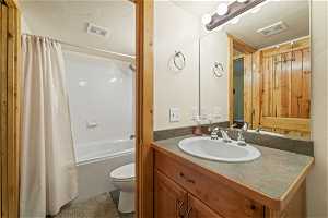 Full bathroom with toilet, vanity with extensive cabinet space, and shower / bath combo with shower curtain