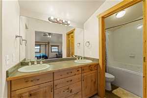 Full bathroom featuring ceiling fan, toilet, double vanity, shower / bathing tub combination, and tile floors