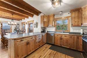 Kitchen with beamed ceiling, sink, dishwasher, hanging light fixtures, and light hardwood / wood-style flooring