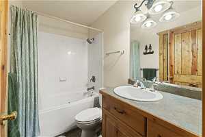 Full bathroom featuring vanity with extensive cabinet space, shower / bathtub combination with curtain, and toilet