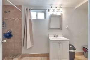Bathroom featuring vanity with extensive cabinet space, tile floors, walk in shower, and a textured ceiling