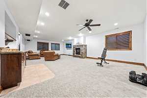 Interior space with a fireplace, ceiling fan, and light carpet