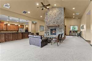 Clubhouse Living room with a stone fireplace, light colored carpet, ceiling fan, and high vaulted ceiling