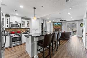 Kitchen featuring white cabinets, a fireplace, pendant lighting, and stainless steel appliances