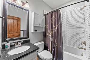 Full bathroom with oversized vanity, shower / tub combo, and toilet
