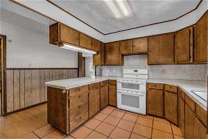Kitchen with kitchen peninsula, light hardwood / wood-style floors, tasteful backsplash, and white electric stove