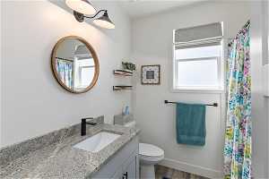 Bathroom with a wealth of natural light, toilet, vanity, and hardwood / wood-style floors
