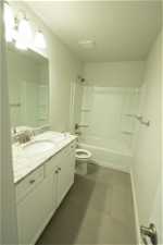 Full bathroom with tile flooring, vanity, toilet, and shower / washtub combination